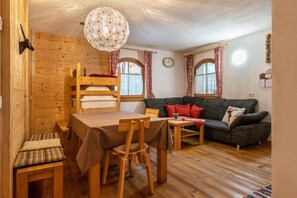 Un intérieur en bois comprenant une table à manger, des chaises, un canapé et un luminaire suspendu.