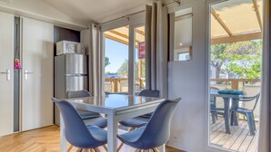 A modern kitchen with a refrigerator, microwave, and dining table with chairs. - Mobile Home 'Le 370' with Shared Pool, Private Terrace and Private Garden Lattes (Lattes)