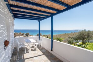 Un espace extérieur abrité, avec une table et des chaises, offrant une vue sur un paysage côtier.