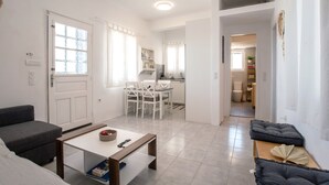 A modern living room with a sofa, a coffee table, and a dining area with chairs and a table. - Holiday Home 'Punda Beach Seaside Retreat' with Sea View, Wi-Fi and Air Conditioning (Paros)