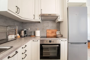 A modern kitchen with white cabinets, a stainless steel refrigerator, a built-in oven, and a coffee maker. - Holiday Home 'Punda Beach Seaside Retreat' with Sea View, Wi-Fi and Air Conditioning (Paros)