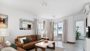 Ein modernes Wohnzimmer mit einem braunen Ledersofa, einem weißen Couchtisch und einem großen Spiegel mit rundem Rahmen.
