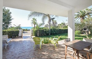A covered patio with a view of the sea, featuring a wooden table and two yellow chairs. - Cozy home in Santa Croce Camerina (Santa Croce Camerina)