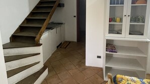 Una escalera que lleva a una plataforma, un armario blanco con puertas de vidrio y una cama con colcha estampada.