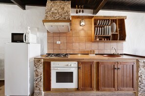 Una cocina con estufa, horno, microondas y armarios de madera.