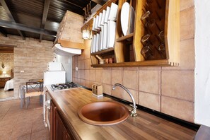 Una cocina con encimera de madera, pileta de cobre, estufa y pared de ladrillo.