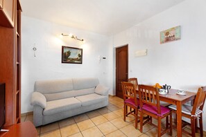 A living room with a sofa, wooden dining table, chairs, a clock, and a painting on the wall. - Apartment 'Trebol 1' with Sea View, Balcony and Wi-Fi (El Mocanal)