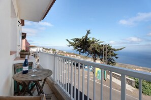 A balcony with a table, a bottle, and a glass. - Apartment 'Trebol 1' with Sea View, Balcony and Wi-Fi (El Mocanal)