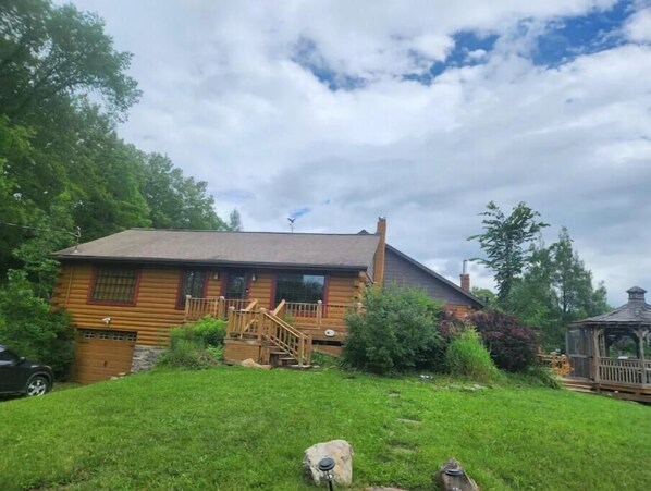Guests can enjoy a serene natural setting with a front porch and staircase leading to the entrance.