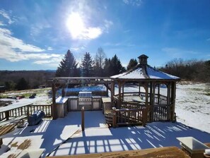 Relax on the outdoor deck with a barbecue grill and seating area under a gazebo.