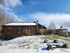 Situated in a natural setting, this cabin features a wooden deck and a gazebo with a conical roof.
