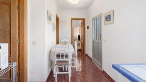 Un couloir étroit avec une porte en bois, une table blanche avec une chaise et un radiateur.