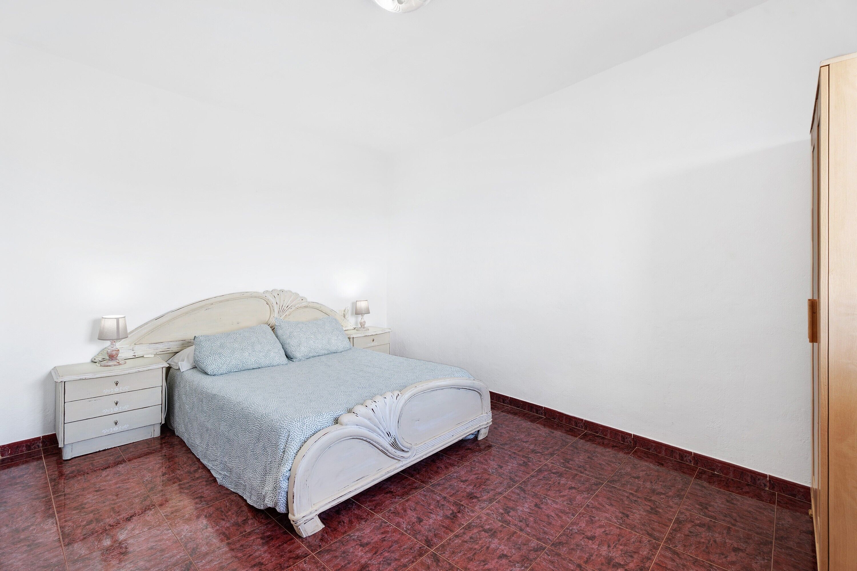 A bedroom with a bed, nightstands, and a wooden door.