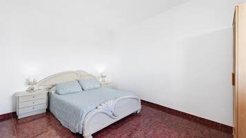 A bedroom with a bed, nightstands, and a wooden door.