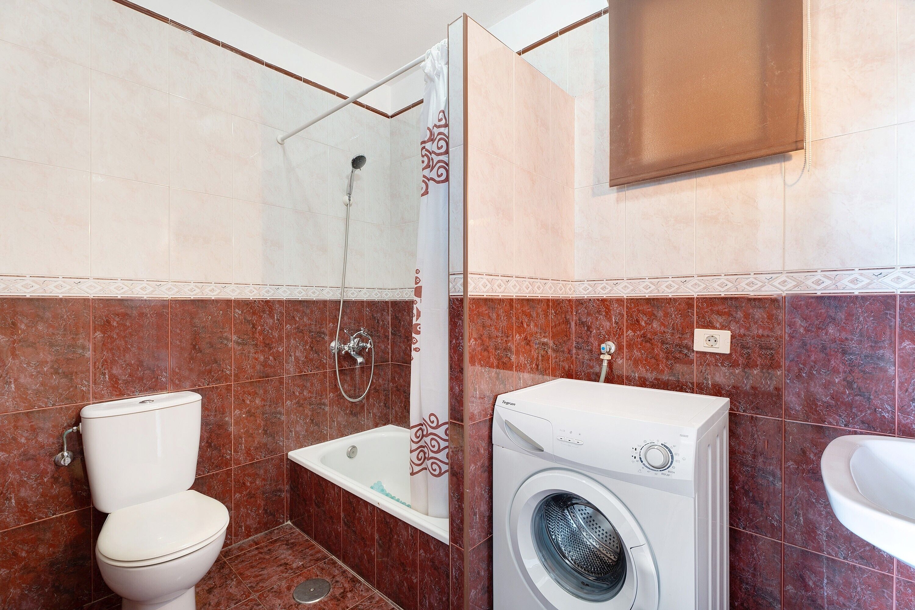 Une salle de bain équipée de toilettes, d’une douche, d’une baignoire et d’un lave-linge.