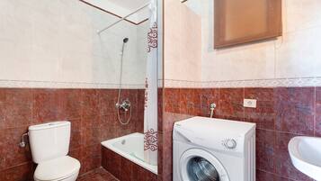 Une salle de bain équipée de toilettes, d’une douche, d’une baignoire et d’un lave-linge.