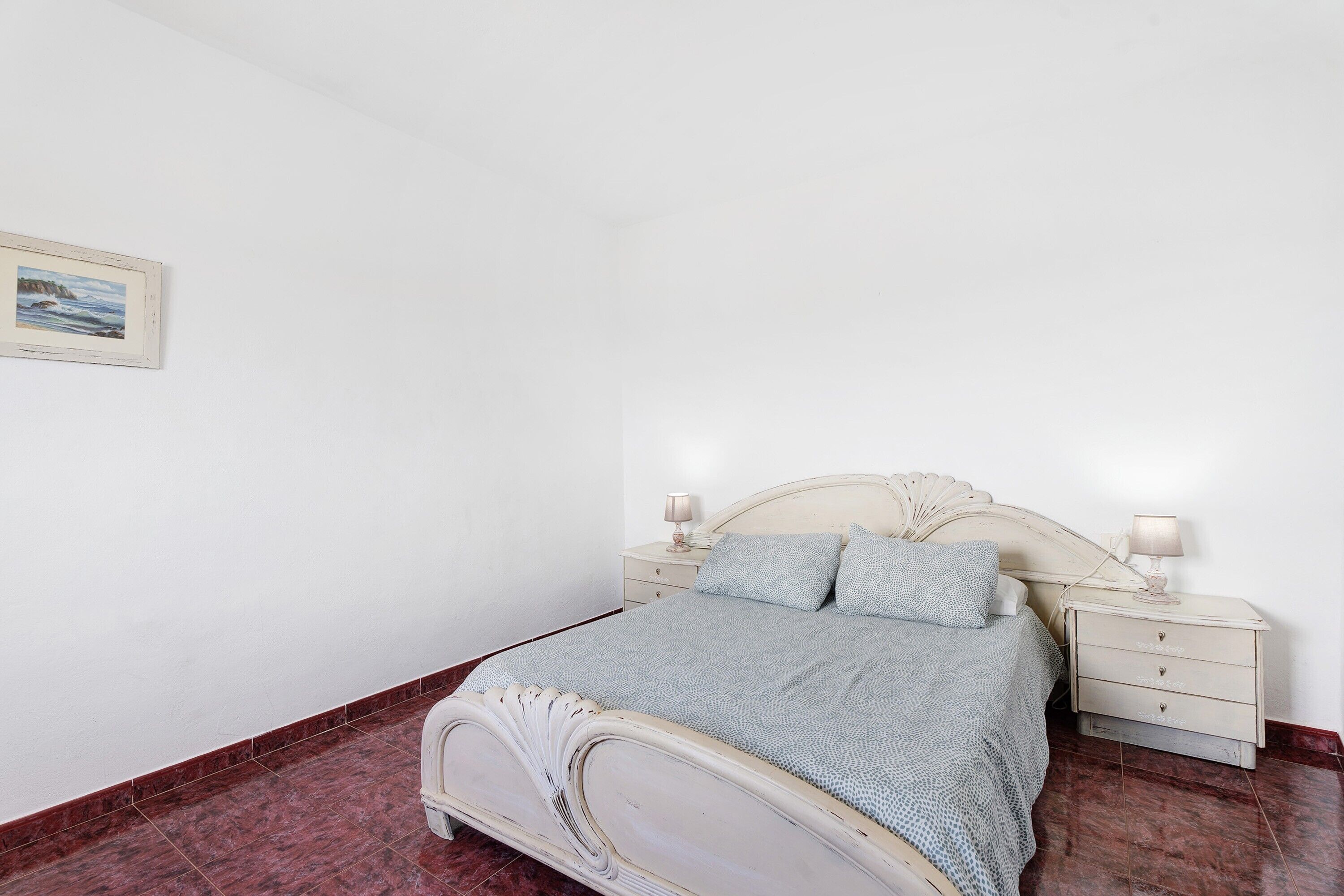 Un dormitorio con una cama, mesitas de noche y un cuadro en la pared.