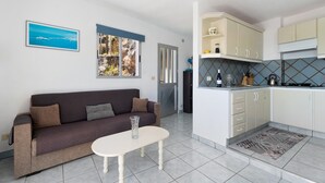 Un salon moderne comprenant un canapé, une table basse et un coin cuisine avec des placards et un pare-feu en carreaux.