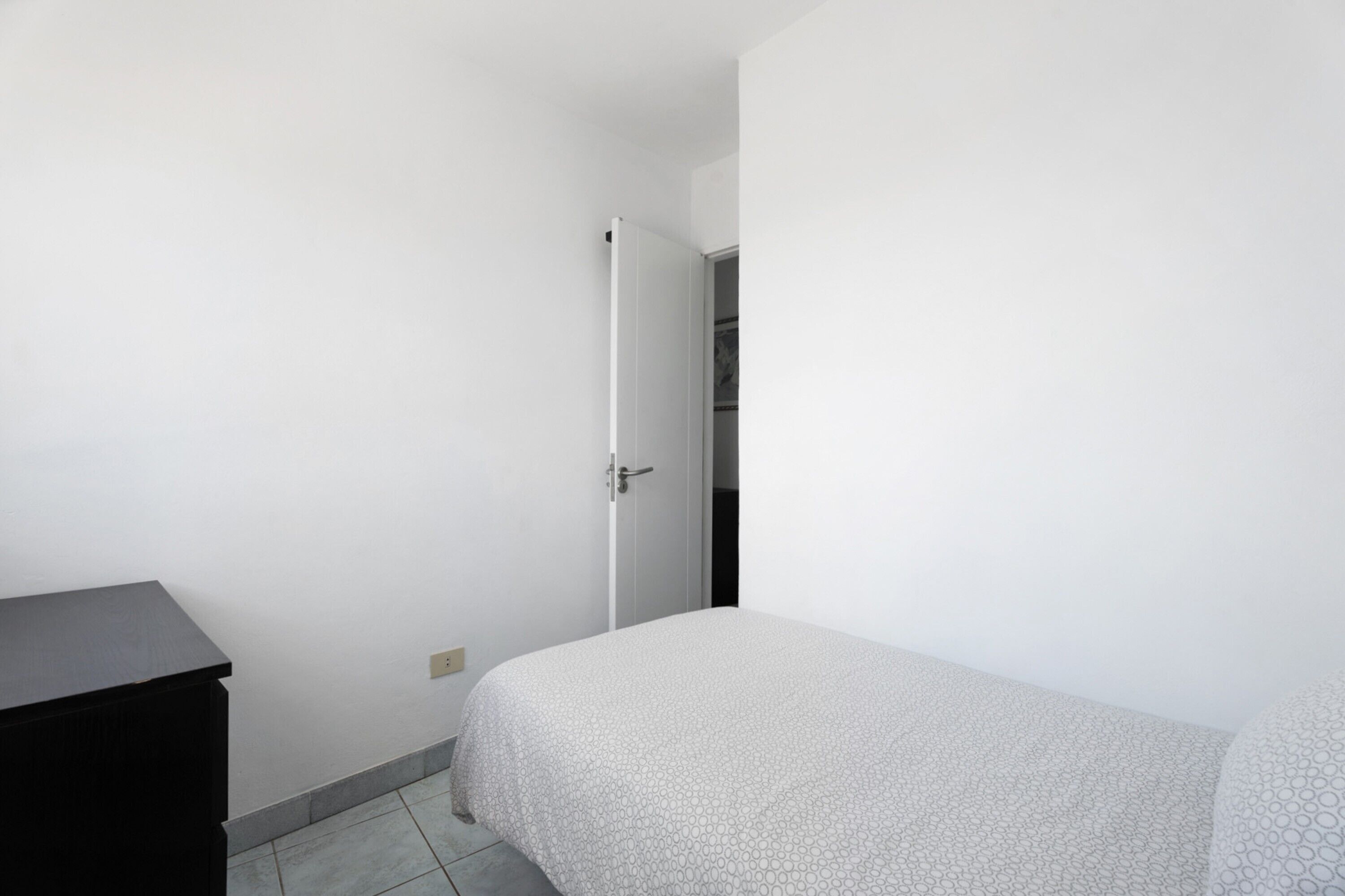 Un dormitorio con cama, cómoda y puerta que da a otra habitación.