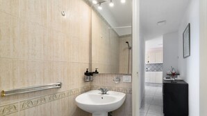 Une salle de bain équipée d’un lavabo, d’un miroir et d’une barre d’appui.