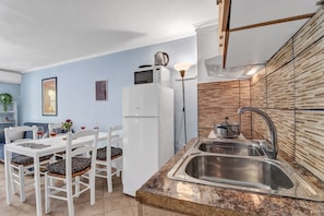 Una cocina moderna con un refrigerador blanco, un fregadero y una zona de comedor con sillas y una mesa blancos.