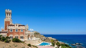 Un bâtiment historique doté d’une tour, d’une piscine et offrant une vue sur la mer.