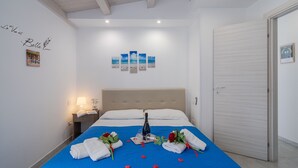 Une chambre d’hôtel avec un lit, une table de chevet, une lampe, un tableau encadré et un mur orné d’un texte et de trois autres tableaux encadrés.