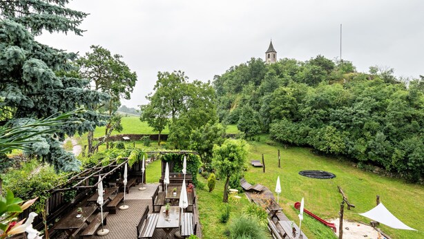A garden with wooden benches, a picnic area, and a view of a hill with a tower. - Studio Apartment 'Zunerhof  Fenn' with Mountain View, Shared Garden and Wi-Fi (Longostagno)