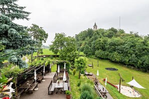 Un jardín con bancos de madera, zona de picnic y vista a una colina con una torre.