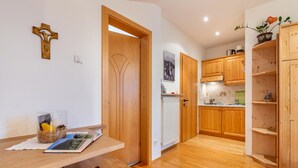A modern kitchen with wooden cabinets, a built-in oven, and a dining area with a table and chairs. - Studio Apartment 'Zunerhof  Fenn' with Mountain View, Shared Garden and Wi-Fi (Longostagno)