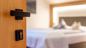 A wooden door with a keyhole and a handle, leading to a bed with a headboard and pillows. - Studio Apartment 'Zunerhof  Fenn' with Mountain View, Shared Garden and Wi-Fi (Longostagno)