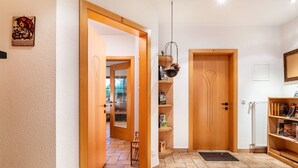 A hallway with wooden doors, a hanging basket, and a doormat. - Apartment 'Zunerhof Abendsonne' with Mountain View, Balcony and Wi-Fi (Lengstein Ritten)