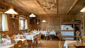 A wooden interior with tables set for dining, wooden chairs, and hanging pendant lights. - Apartment 'Zunerhof Abendsonne' with Mountain View, Balcony and Wi-Fi (Lengstein Ritten)