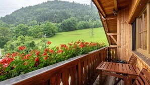 A wooden balcony with a table and chairs, overlooking a green landscape with trees and a hill. - Apartment 'Zunerhof Abendsonne' with Mountain View, Balcony and Wi-Fi (Lengstein Ritten)