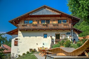 Een houten chalet met balkon, een eethoek en een bordje met de tekst 'Gasthof Zun'.