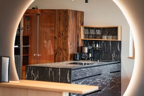 Une cuisine moderne dotée d’un plan de travail en marbre, de meubles en bois et d’un espace café intégré.