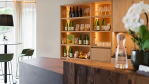 Una cocina moderna con estantes de madera, botellas de vino, copas y una orquídea en maceta.