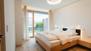 Un dormitorio moderno con una cama de madera, una mesita de noche y vistas a un espacio exterior por una puerta de vidrio.