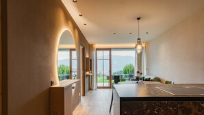 Une cuisine moderne dotée d’un plan de travail en marbre, de meubles en bois et offrant une vue sur l’extérieur.