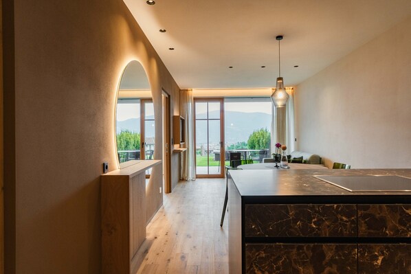 A modern kitchen with a marble countertop, wooden cabinets, and a view of the outdoors.