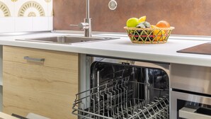 Una cocina con lavavajillas, un fregadero y una cesta de frutas en la encimera.