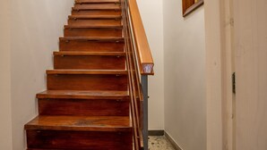 Una escalera de madera con barandilla que lleva a una puerta con un pequeño ventanal.