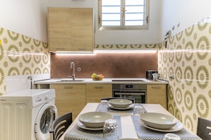 A compact kitchen with a washing machine, a sink, and a dining area with a table set for two.