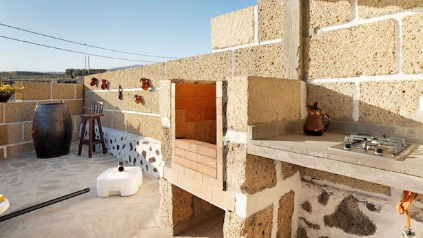A stone exterior with a brick oven, a white gas cylinder, and a wooden chair. - 'Eva' with Sea View, Private Terrace and Wi-Fi (GRANADILLA DE ABONA)