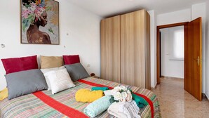Un dormitorio con cama, almohadas, un cuadro y un armario de madera.