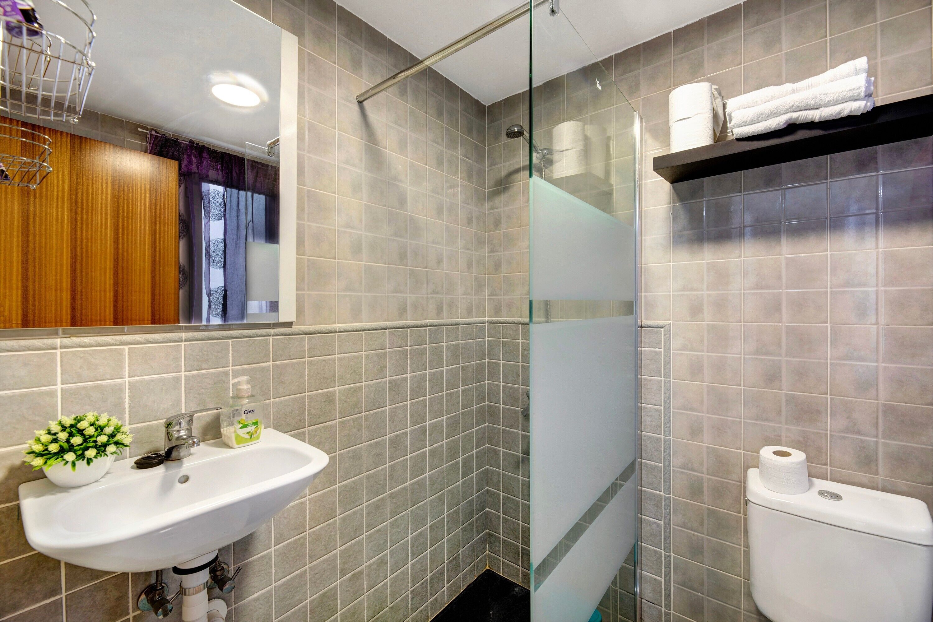 A bathroom with a sink, mirror, shower, and toilet.