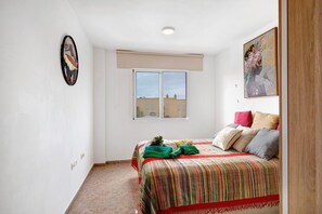 Une chambre à coucher avec un lit, une fenêtre, un tableau et une porte.