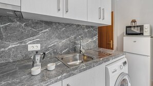 A modern kitchen with a marble countertop, stainless steel sink, and a Bosch washing machine.