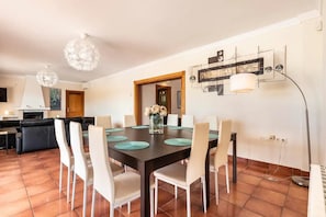 A dining area with a dark wooden table, white chairs, and a vase of flowers.
