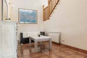 A room with a white sofa, a small table, a radiator, and a staircase with wooden railings. - Villa 'Can Pedra Junto A Playa Den Bossa' with Sea View, Wi-Fi and Air Conditioning (Ibiza)